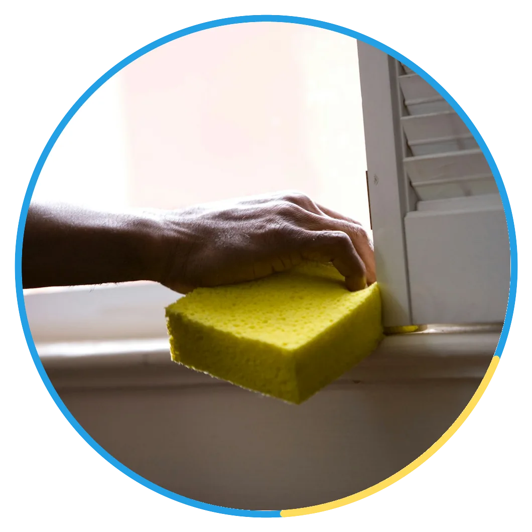 Up Services cleaner wiping a window sill with a sponge, brand seal on the photo
